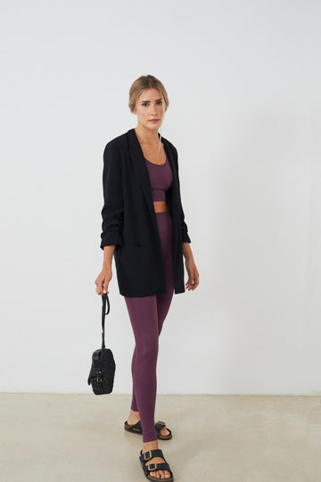 Conjunto yoga mujer marca NOY (not only yoga) modelo GAIA y top AINE con volantes sin costuras tono cereza pansy plum combinado con chaqueta negra bolso y sandalias negras