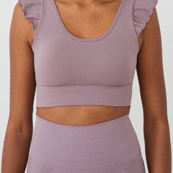 Vista frontal top yoga mujer marca NOY (not only yoga) modelo AINE con volantes tono rosa Lotus pink
