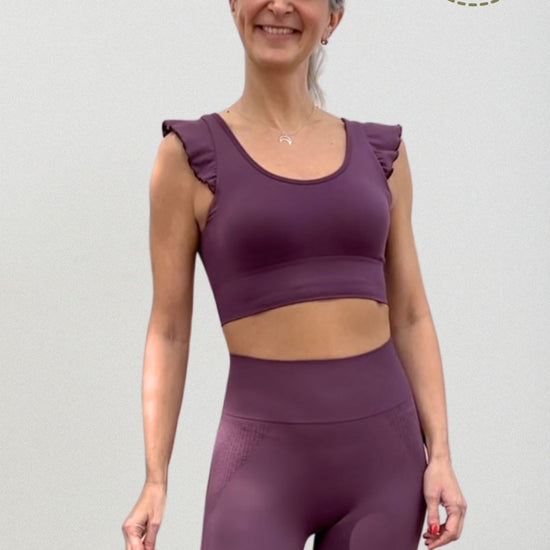 Vista frontal top yoga mujer marca NOY (not only yoga) modelo AINE con volantes tono cereza pansy plum