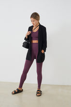 Cargar imagen en el visor de la galería, Conjunto yoga mujer marca NOY (not only yoga) modelo GAIA y top AINE con volantes sin costuras tono cereza pansy plum combinado con chaqueta negra sandalia negra y bolso
