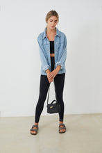 Cargar imagen en el visor de la galería, Conjunto yoga mujer marca NOY (not only yoga) modelo GAIA y top SELENE sin costuras con tirantes tono nergo black lava combinado con camisa vaquera bolso y sandalias negras
