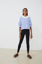 Cargar imagen en el visor de la galería, Sudadera mujer con CUELLO independiente tipo volante  NOY (not only yoga) modelo Chlöe de algodón orgánico blanco atado con lazo en la parte trasera y combinado con legging negro y sandalias  negras
