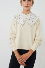 Cargar imagen en el visor de la galería, Sudadera con CUELLO independiente NOY (not only yoga) modelo CLAIRE de algodón orgánico estampado con flores en tonos neutros atado con botón en la parte delantera combinado con legging negro
